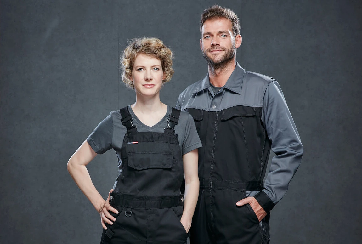 Das Bild zeigt zwei Auszubildende, die moderne Berufsbekleidung tragen. Diese Kleidung bietet optimalen Schutz und Komfort und stärkt das Wir-Gefühl im Team.  